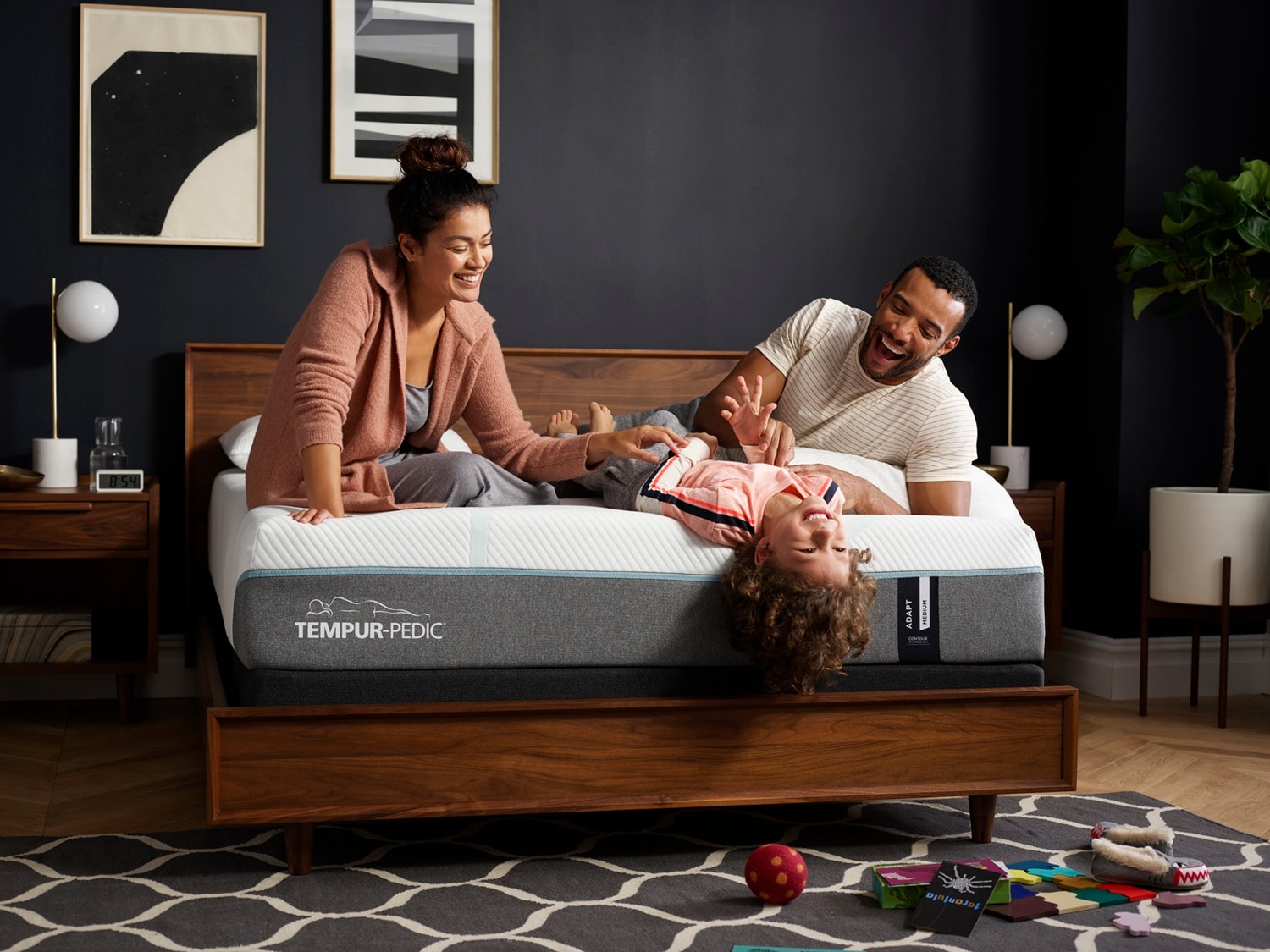 Woman and man laughing with their child on Tempur-Pedic mattress