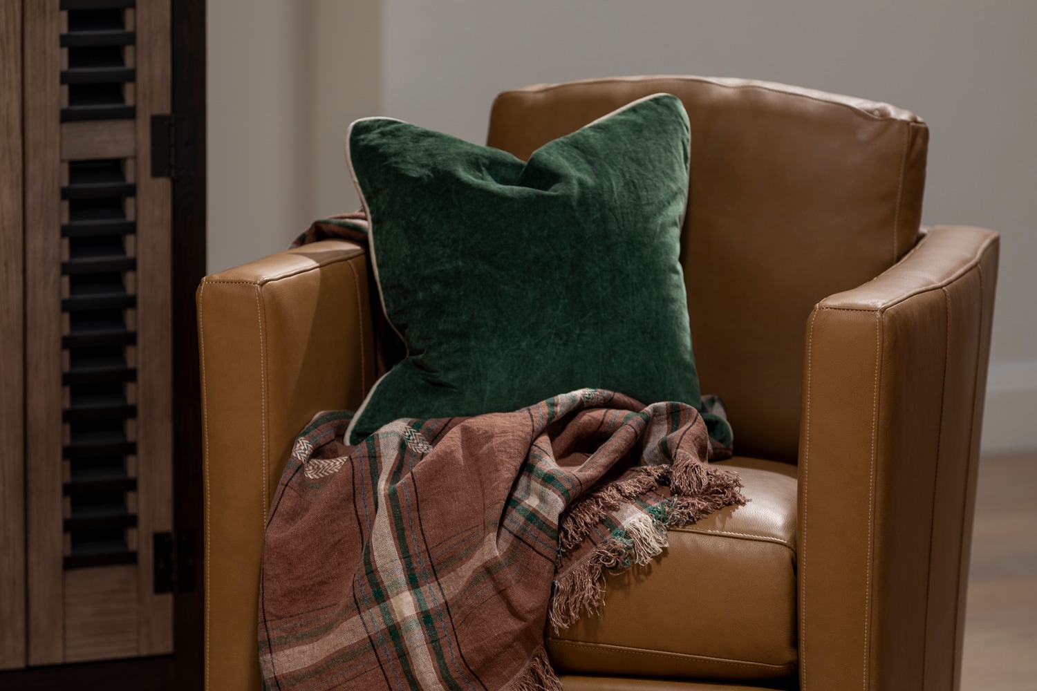 Brown leather swivel chair with linen throw and velvet green pillow