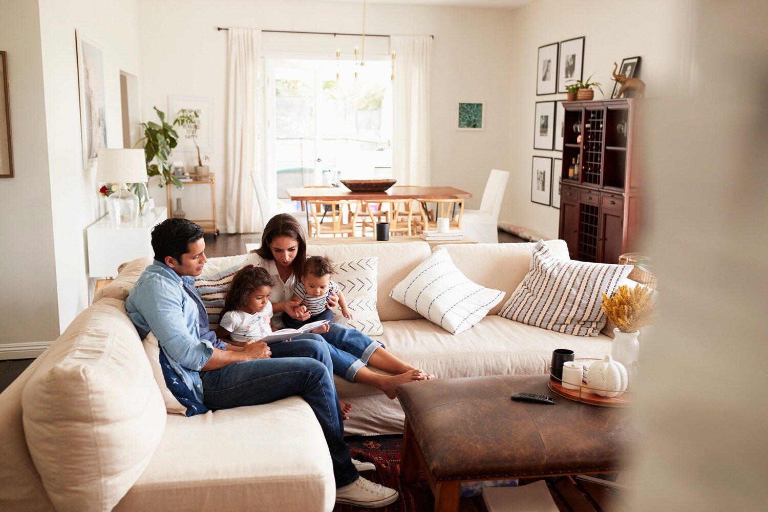 A family of four reading together on a beige sectional