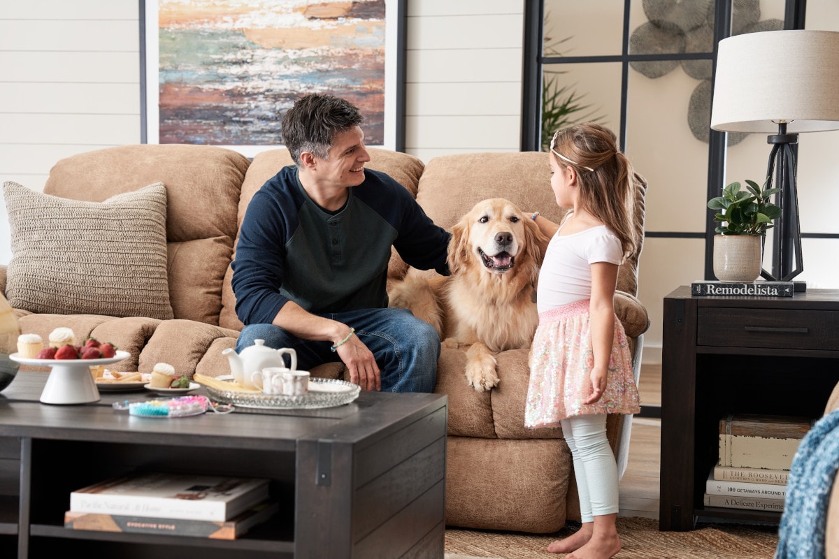 a man, a dog, and a little girl enjoy family time on brown reclining la-z-boy sofa